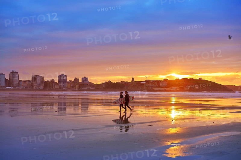 Gijon sunset San Lorenzo beach with surfers in Asturias of spain