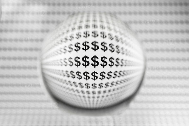 Studio shot of a glass sphere on a sheet of paper with dollar signs