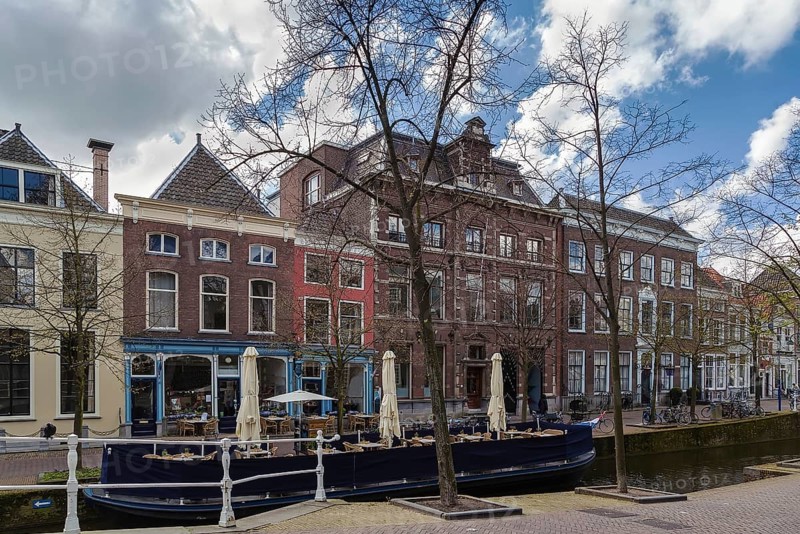 View of Delft canal with historic houses and boat, Netherlands