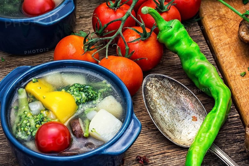 Traditional soup of fresh vegetables in blue pot on wooden background.Photo tinted