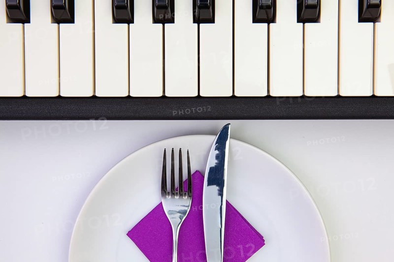 Symphony of taste. White plate and piano keys on the white wooden table.Top view. Flat Lay Image
