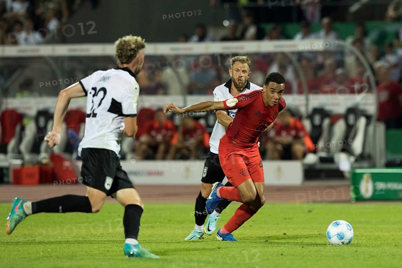 Football match, Jamal MUSIALA FC Bayern Munich right escapes with ball captain Johannes REICHERT SSV Ulm, left Philipp STROMPF SSV Ulm observes the situation, football stadium Donaustadion, Ulm, Germany, Europe