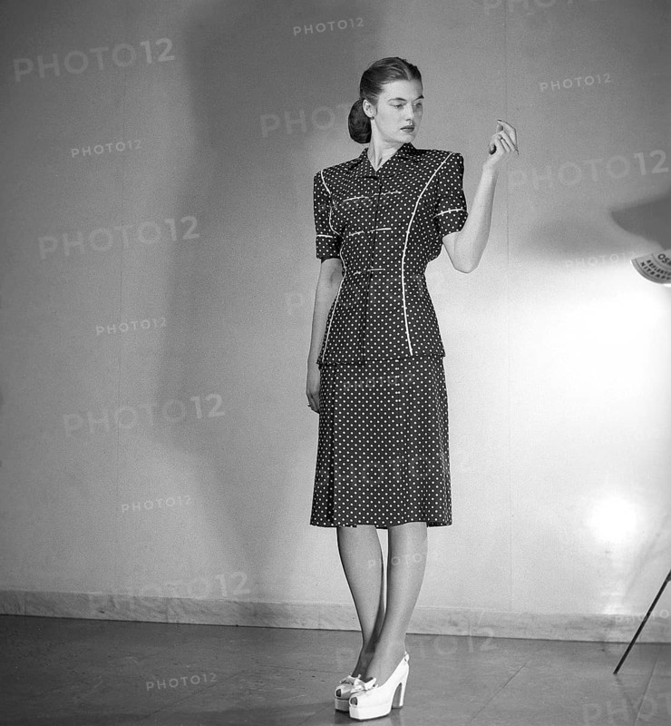 Fashion 1946, a young female model dressed in the fashion of the post war era. The dress with short sleeves reaching below the knees is in dark fabric with a pattern of white dots. Kristoffersson ref Y86-6