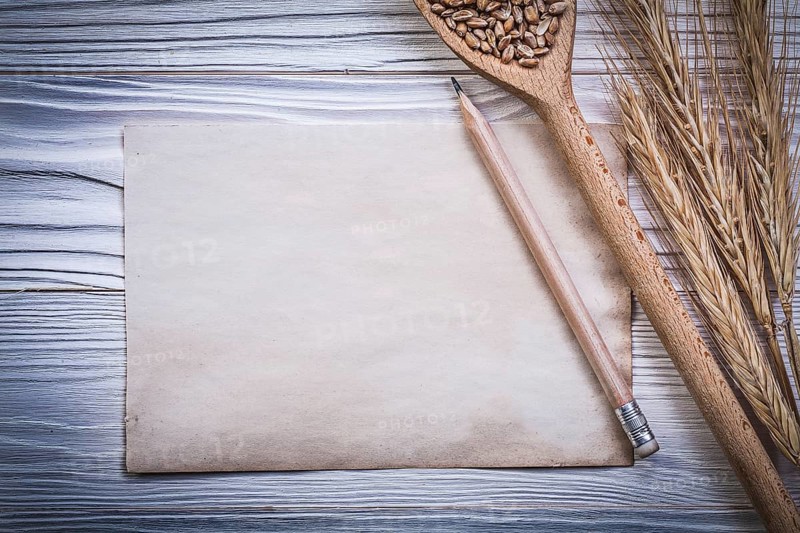 Bunch of wheat-rye ears wooden spoon corn pencil vintage paper on wood board