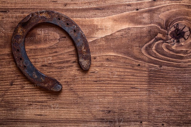 Single vintage rusted horseshoe on old wooden board with copyspace happy concept