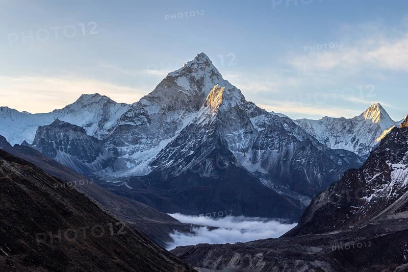 Ama Dablam mountain at sunrise and blue sky. Sun illuminates slopes. Himalayan mountains, Nepal, Asia