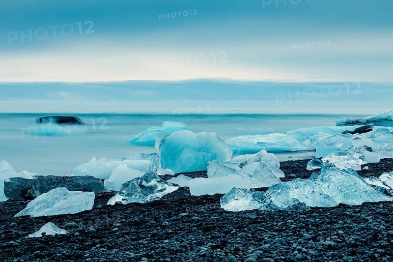 Ice formations along the ocean shoreline under a serene blue sky, creating a cold feeling, Expansive icy scene with glaciers and rugged mountains, capturing a serene, cold atmosphere, iceberg, glacier, snow, ice rock, ice diamont, glacier lagoon, nature, snow, diamont beach, Iceland, Europe