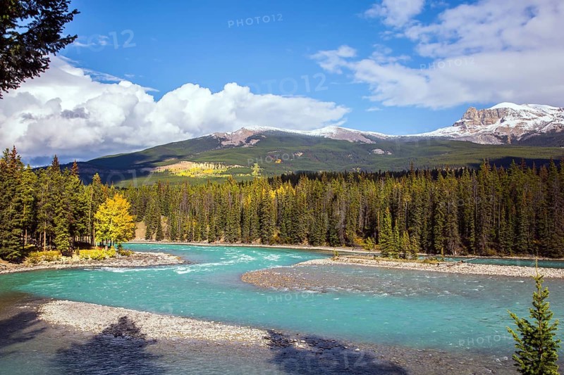 Mountain river with icy melt water from glaciers. Mountain peaks are covered with snow. The Rocky Mountains of Canada