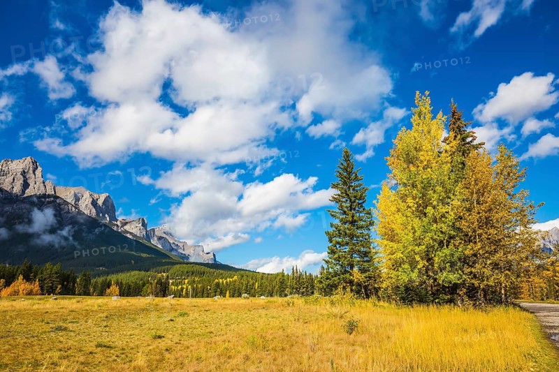 The Three Sisters mountains in Canadian Rockies. Shining autumn day in Canmore. Mountain peaks and white clouds. Concept of niking