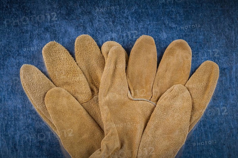 Leather brown construction gloves on scratched metallic surface close up version building concept