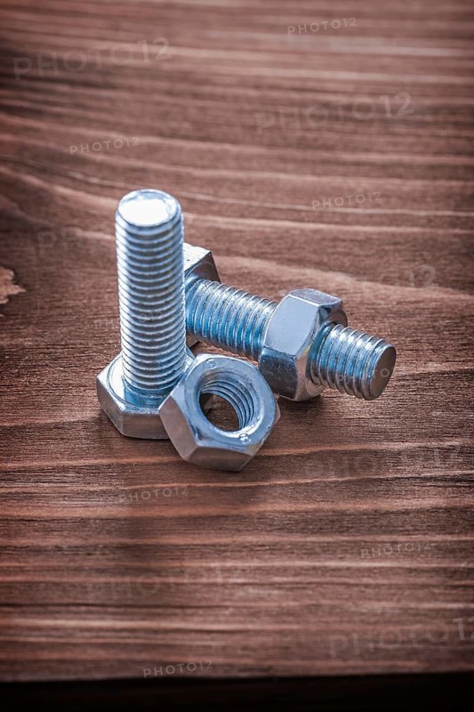 Stainless bolts and nuts on brown wooden board construction concept
