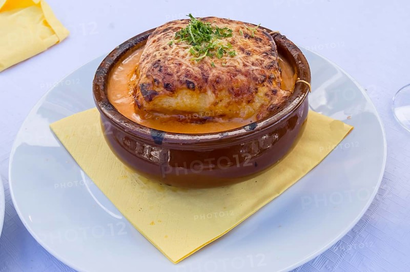 Portion of lasagna bolognese in a terracotta ramekin lay on a white plate
