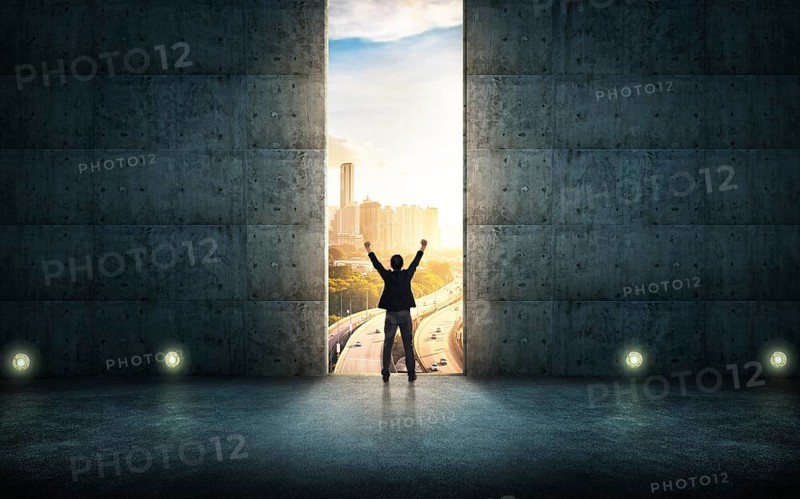 Success businessman cheering against concrete wall with huge door, sunrise scene city skyline outdoor view