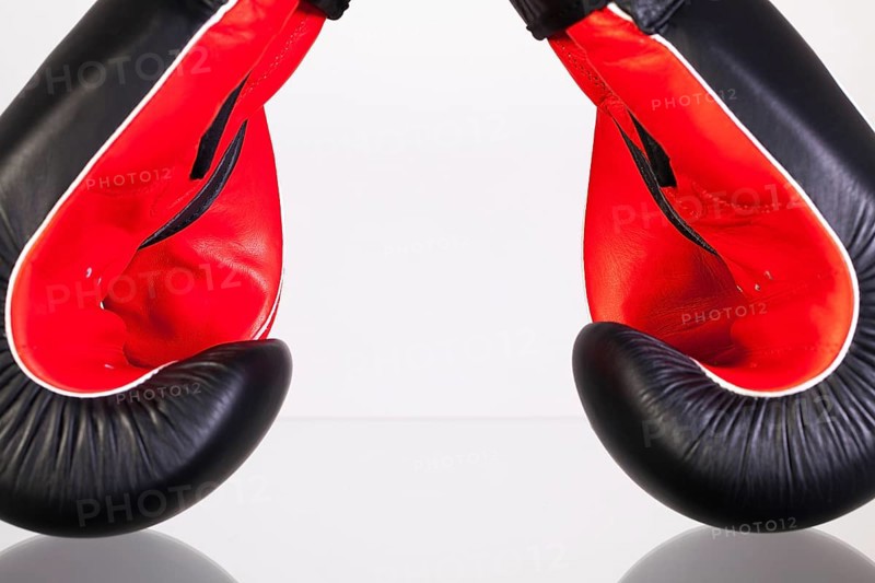 Red and black boxing gloves on a glass table isolated on white background