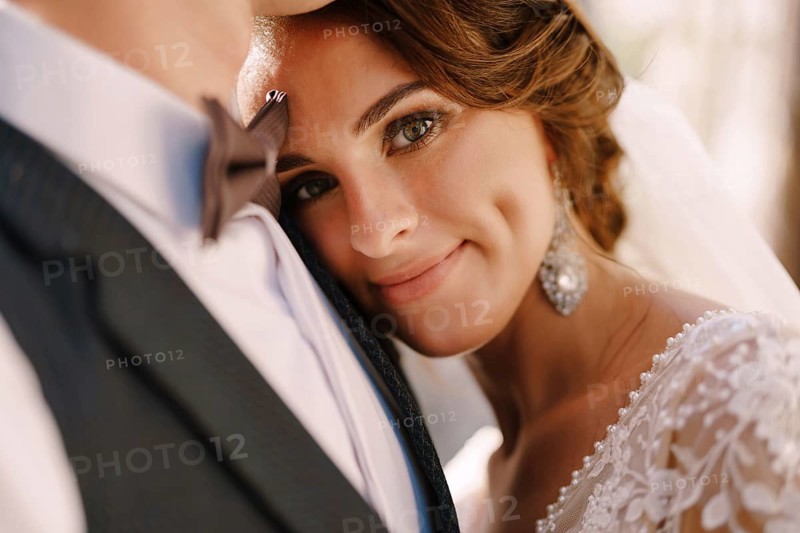 Close-up portrait of a bride looking at the camera, laid her head on the groom's chest. Beautiful wedding couple. Fine-art wedding photo in Montenegro, Perast