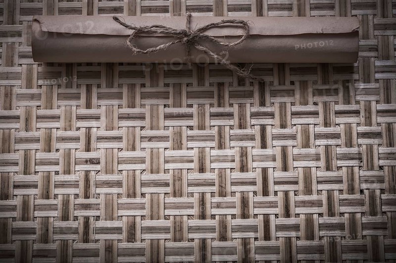 Vintage rolled document with string on wicker wooden mat