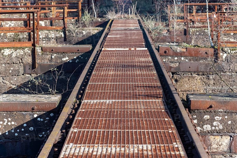 Rusted metal walkway in an industrial setting with grid pattern