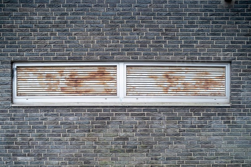 Rusted ventilation grilles in a brick wall