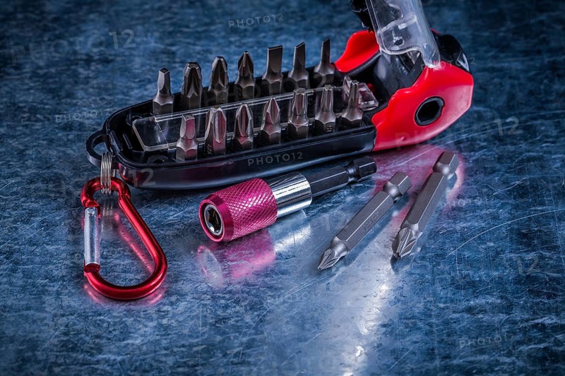 Screwdriver with muunction bit set on scratched metallic background