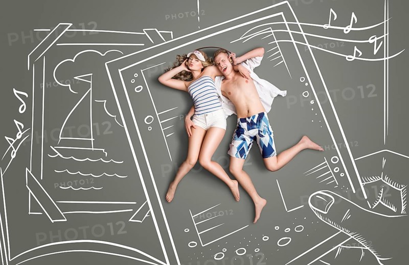Happy valentines love story concept of a picture of a romantic couple, sharing headphones and listening to the music against chalk drawings background of a photo book