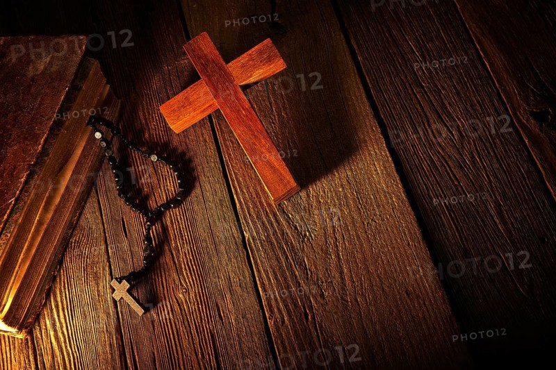 Christian cross on wood bible and rosary beads over wooden vintage background