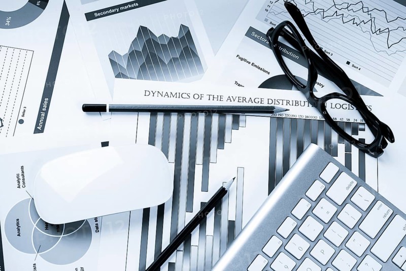 Business workplace with keyboard glasses and financial documents on table