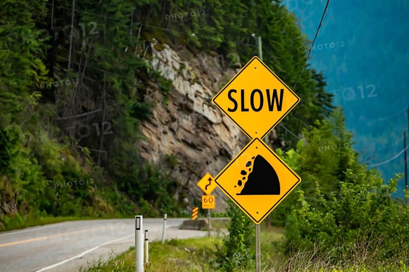 Slow, Watch for fallen rock and be prepared to avoid a collision, Warning yellow roads signs in selective focus view with rocky slope background