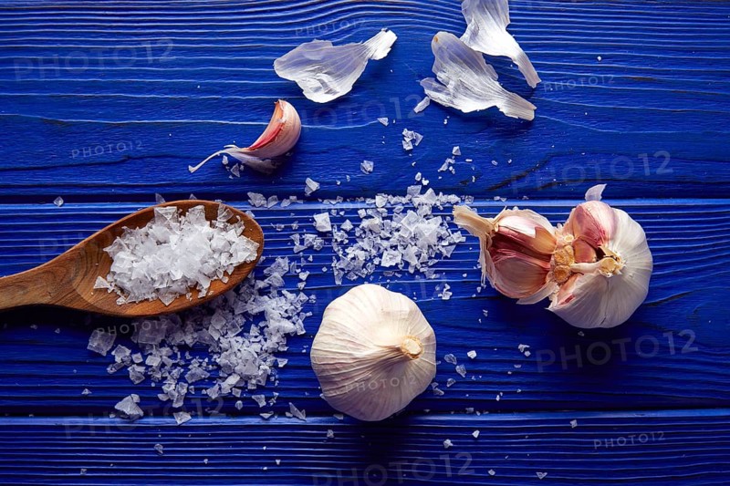 Garlic and salt spread on a blue wooden table with casual composition