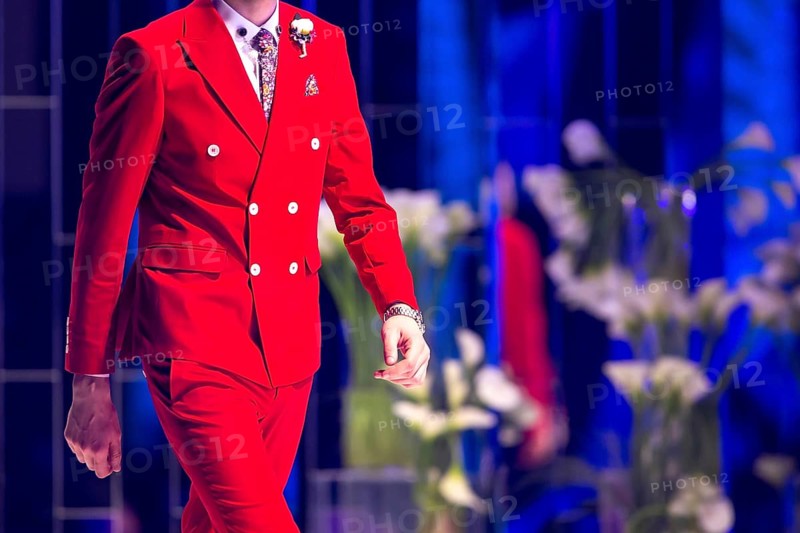 Male model walks the runway in red suit during a Fashion Show. Fashion catwalk event showing new collection of clothes. Single model