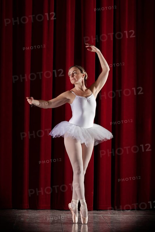 Ballet dancer in white ballet tutu in front of a red stage curtain in elegant pose, Mindelheim City Theatre, Mindelheim, Bavaria, Germany, Europe