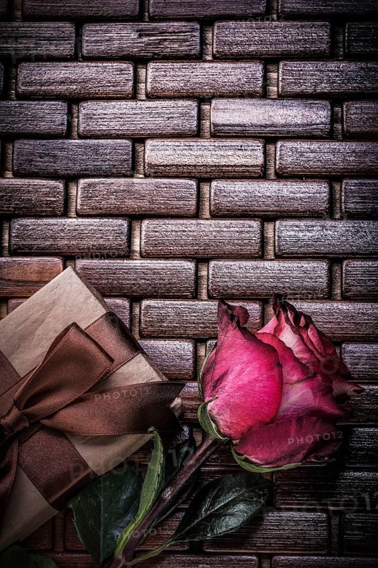 Red fragrant rose wrapped giftbox on wicker wooden matting