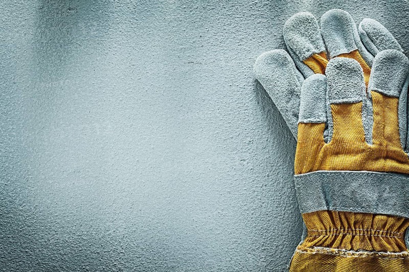 Pair of protective gloves on concrete background copy space