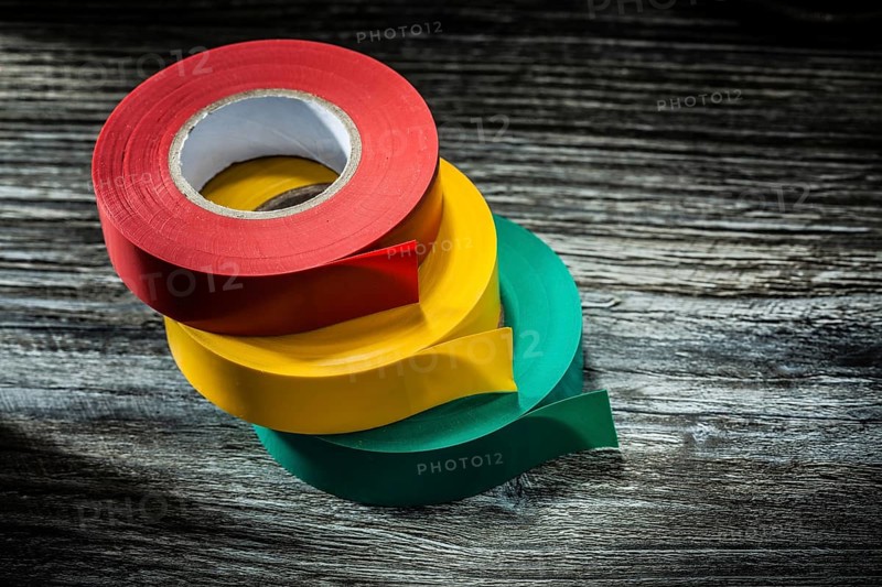 Rolled electricians tapes on wooden board