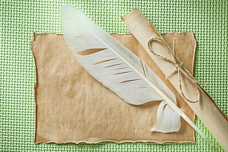 Vintage sheet paper roll quill on green surface horizontal view