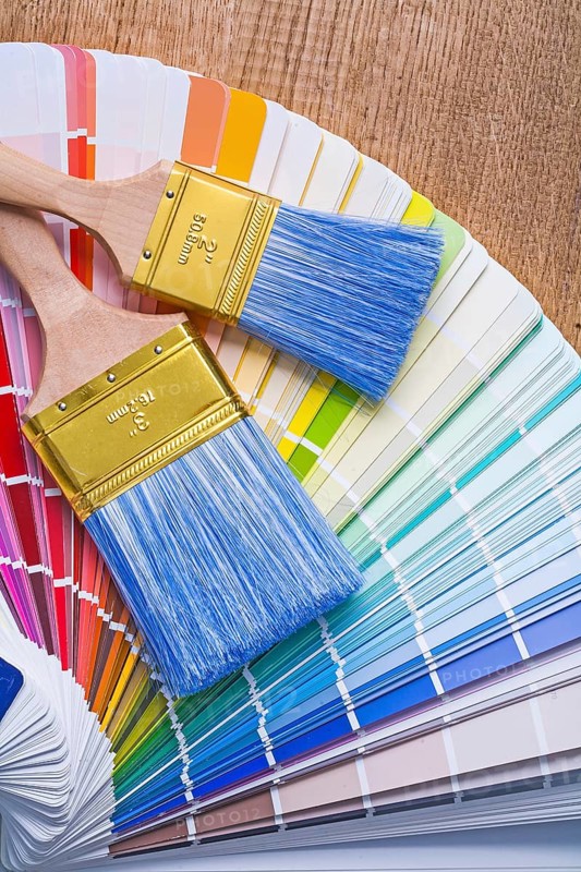 Two paintbrushes on color palette and wooden board