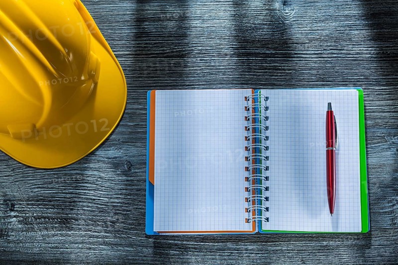 Notepad pen building helmet on wooden board