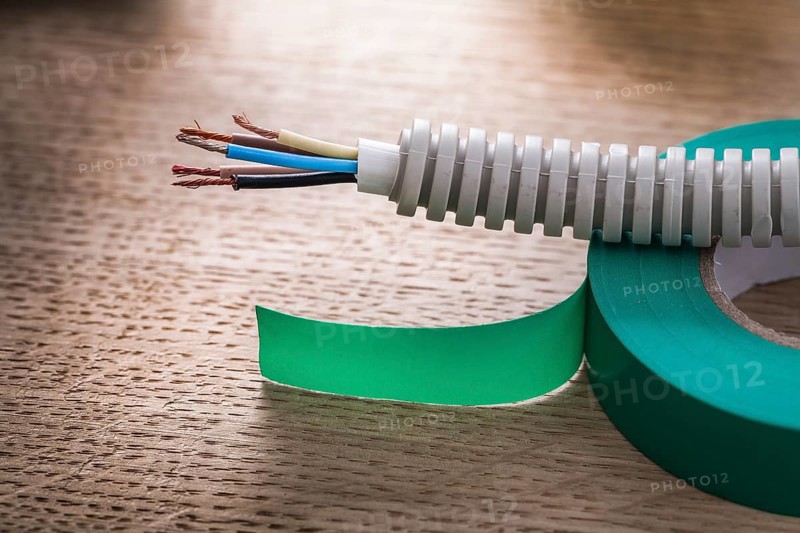 Electric cable in corrugated pipe on roll of green insulating tape