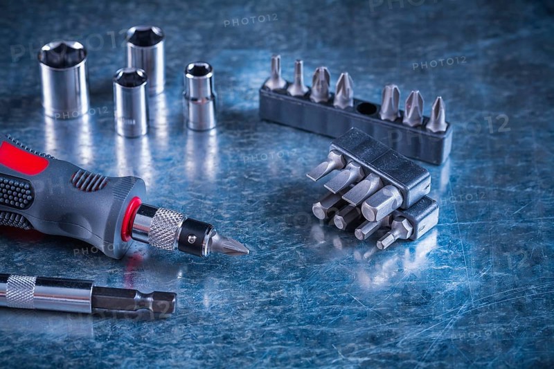 Toolset of screwdriver with stainless replaceable bits and torx on scratched metallic background construction concept