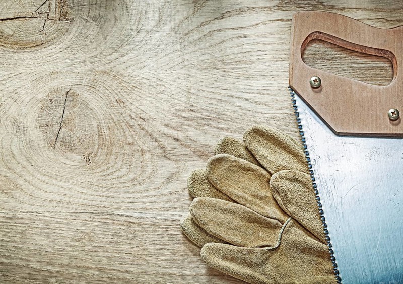 Safety gloves hacksaw on wooden board construction concept