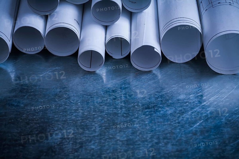Rolls of white blueprints on scratched metallic background building and architecture concept