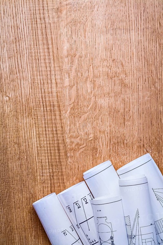Stack of white construction rolled up blueprints on wooden boards with copyspace