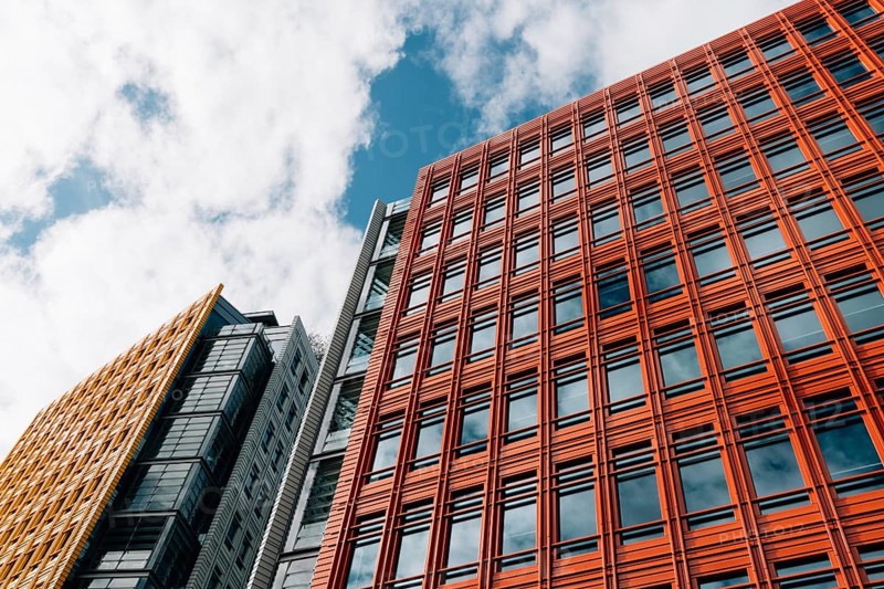 London, UK, August 27, 2023: Low angle view of modern and colorful apartment and office buildings in the City of London. Central Saint Giles in the West End. View against blue sky with white clouds with space for copy