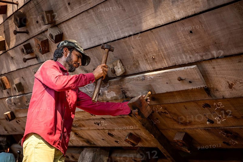 Shipbuilders working on a wooden boat under construction, Mandvi, Gujarat, India, Asia