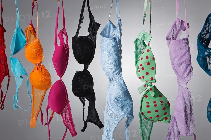 A group of colorful bras hang on a clothes line in a studio environment