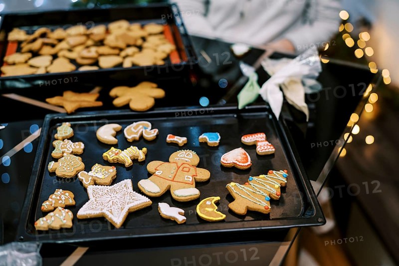 Gingerbread cookies with colorful ornaments lie on a baking sheet on the table.