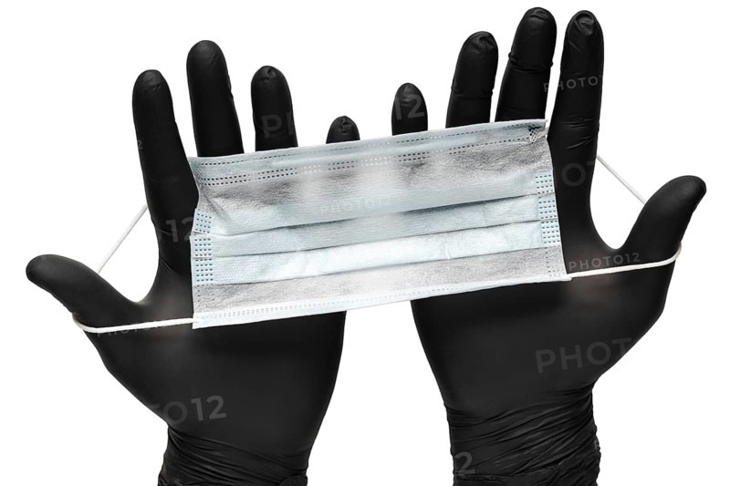 Medical man holds antivirus face mask in hands in black medical gloves. Isolated on white background. Pandemic insurance, airborne diseases, SARS, grippe. Medical masks for human cover nose and mouth
