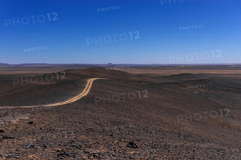 A view of a dirt road leading through the rock and sand desert of southeastern Morocco mear Merzouga and Erg Chebbi