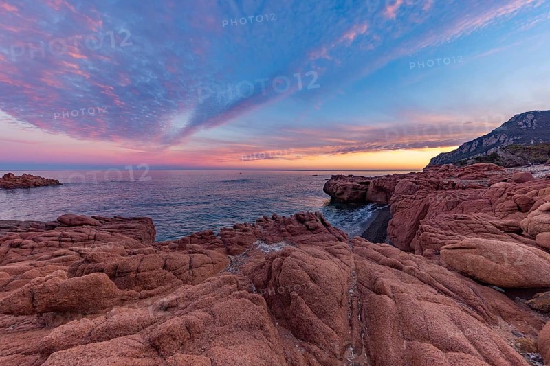 Large red rocks at the edge of the sea under a cloudy evening sky, Spiaggia di Cala E'Luas, Ogliastra, Sardinia, Italy, Europe