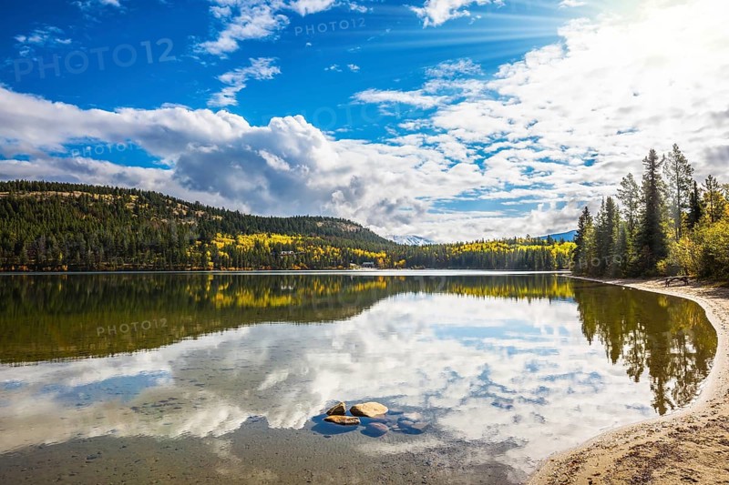 Pyramid Mountain and cumulus clouds is reflected in Pyramid Lake. Cold autumn morning in the Rocky Mountains, Canada, North America