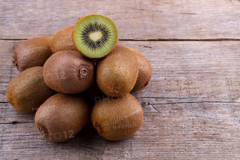 Pile of fresh kiwi on an old wooden board